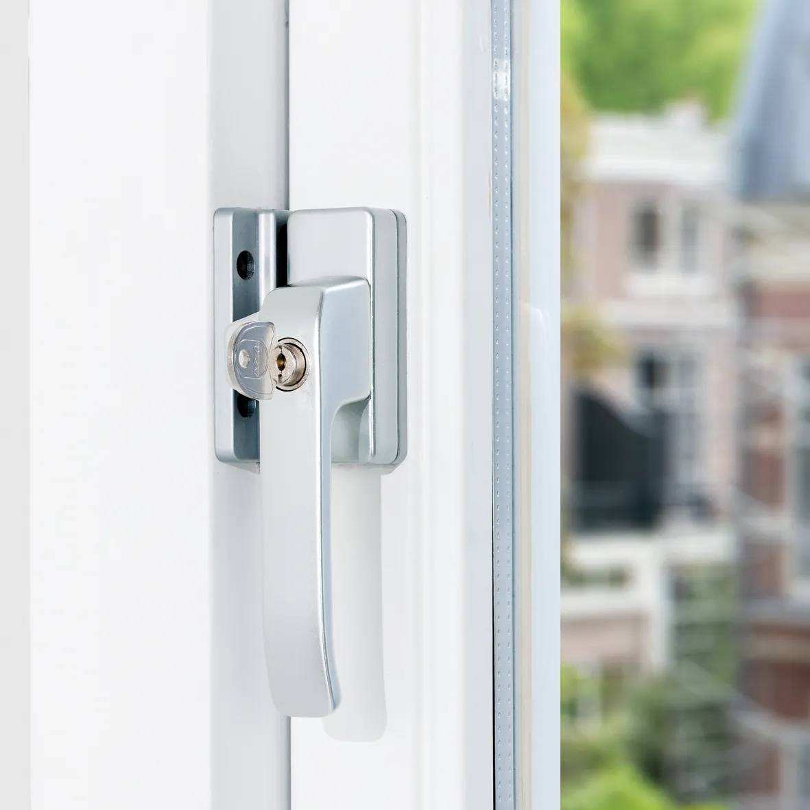 Axa 3329 opbouw raamboompje in aluminium kleur met sleutel, gemonteerd op wit kozijn in gesloten stand
